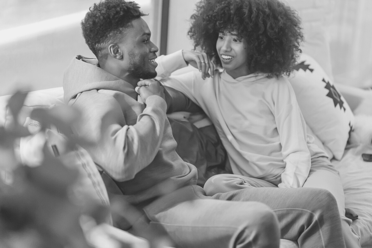 Happy black couple in domestic clothes talking in lounge